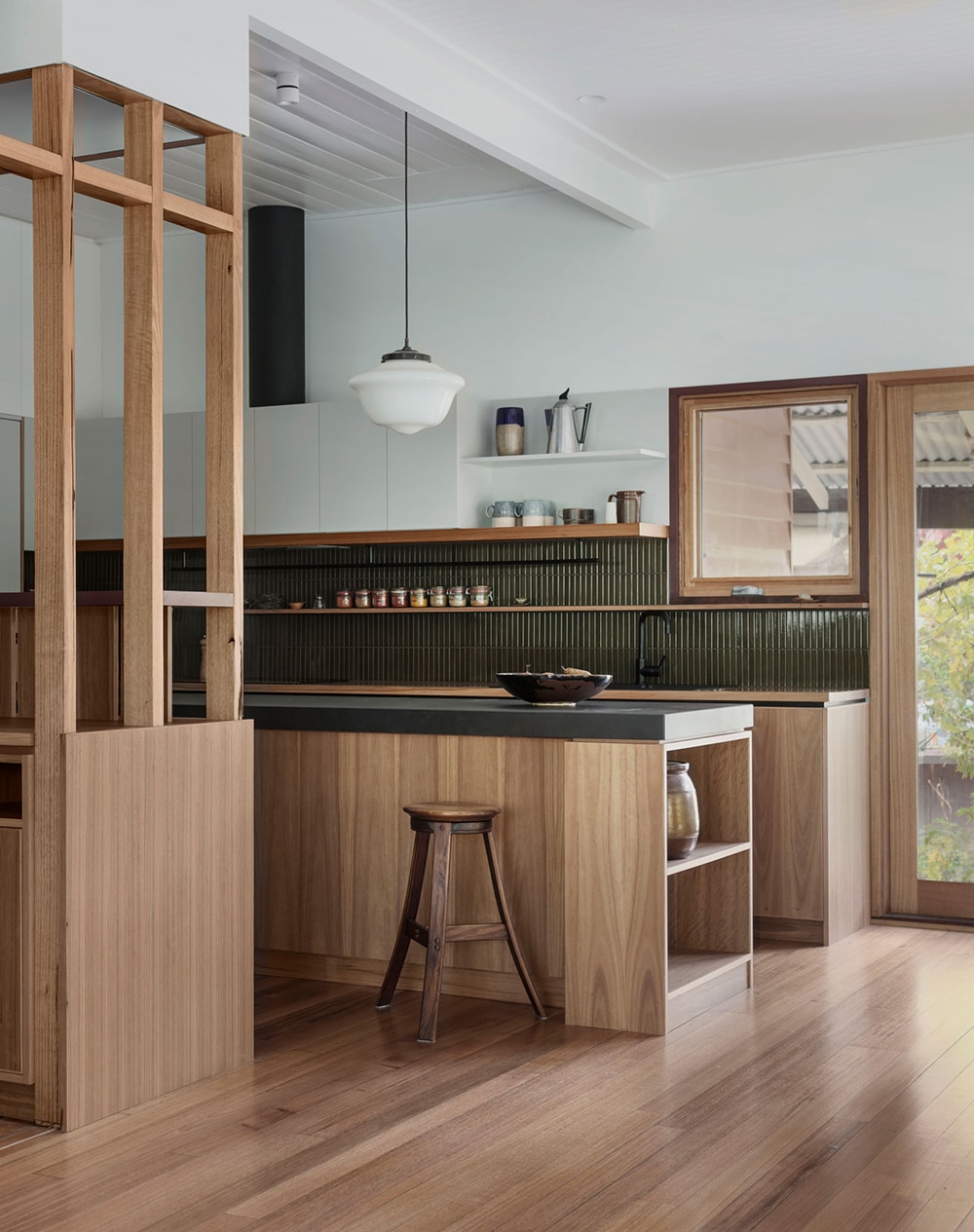 A modern kitchen with neutral oak slab doors and a deep green tiled backsplash.