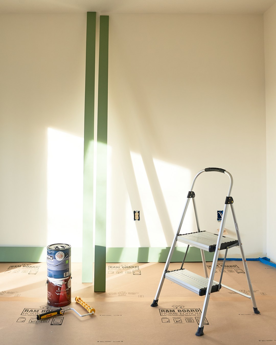 Warm white bedroom with green trim and paint supplies